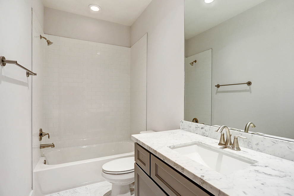 This is an example of a contemporary 3/4 bathroom in Houston with recessed-panel cabinets, brown cabinets, an alcove tub, a shower/bathtub combo, a two-piece toilet, white tile, ceramic tile, white walls, an undermount sink, quartzite benchtops, white floor, a shower curtain and white benchtops.