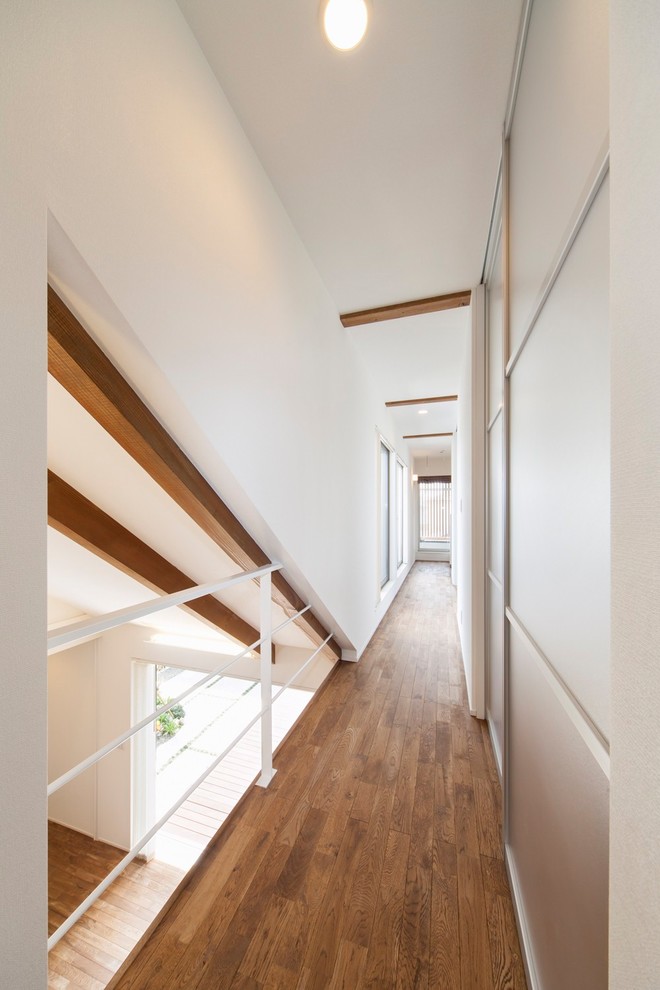 This is an example of a hallway in Other with white walls and brown floor.