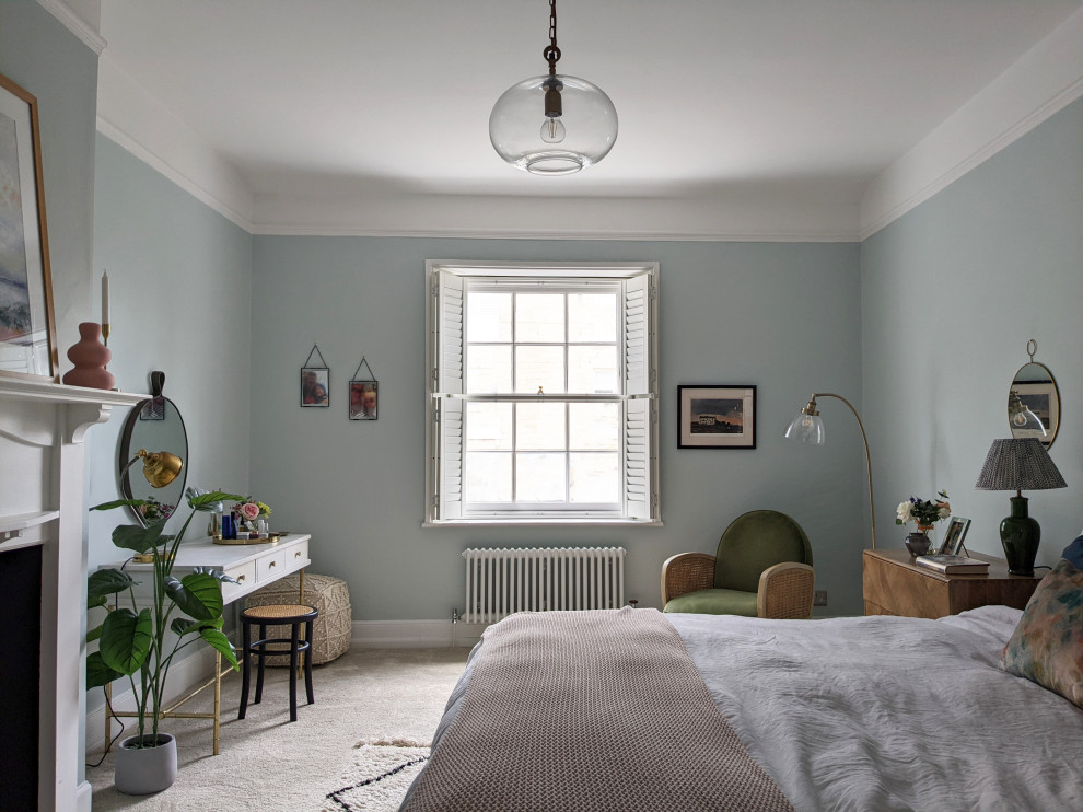 Cette photo montre une grande chambre éclectique avec un mur bleu, une cheminée standard, un manteau de cheminée en bois et un sol beige.