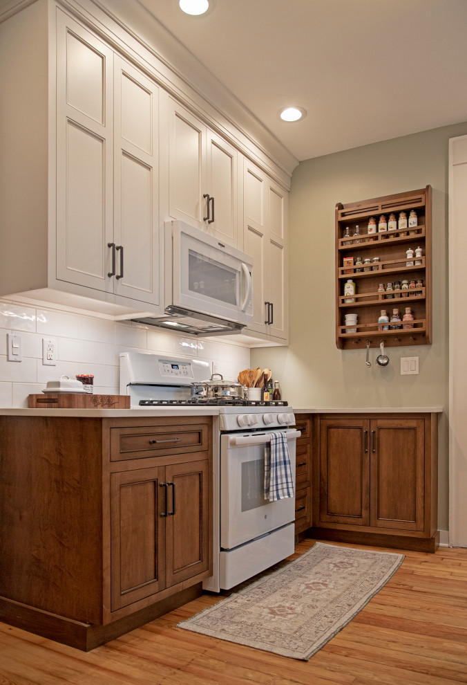 Example of a small transitional light wood floor and brown floor enclosed kitchen design with an undermount sink, quartz countertops, white backsplash, ceramic backsplash, white appliances, no island, white countertops, shaker cabinets and white cabinets