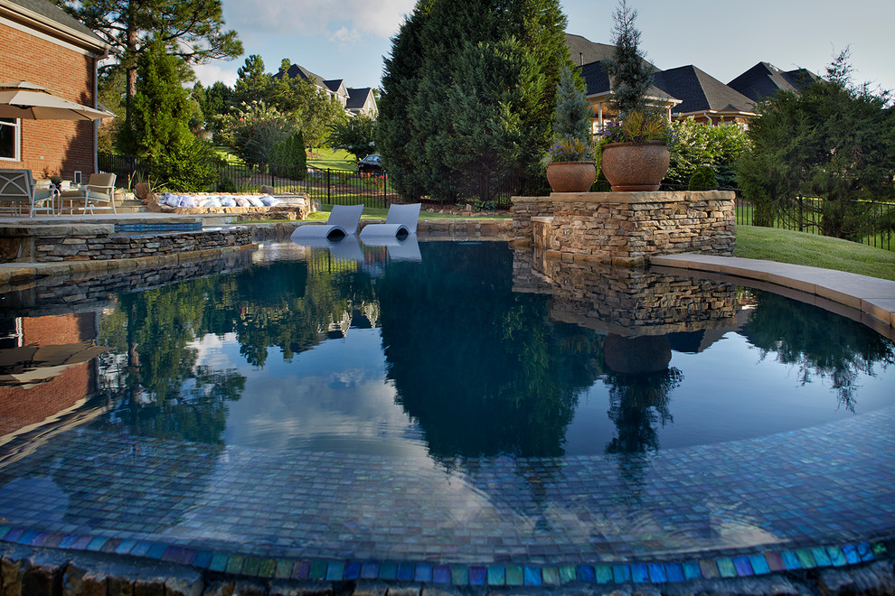 This is an example of a mid-sized eclectic infinity pool in Charlotte with a water feature.