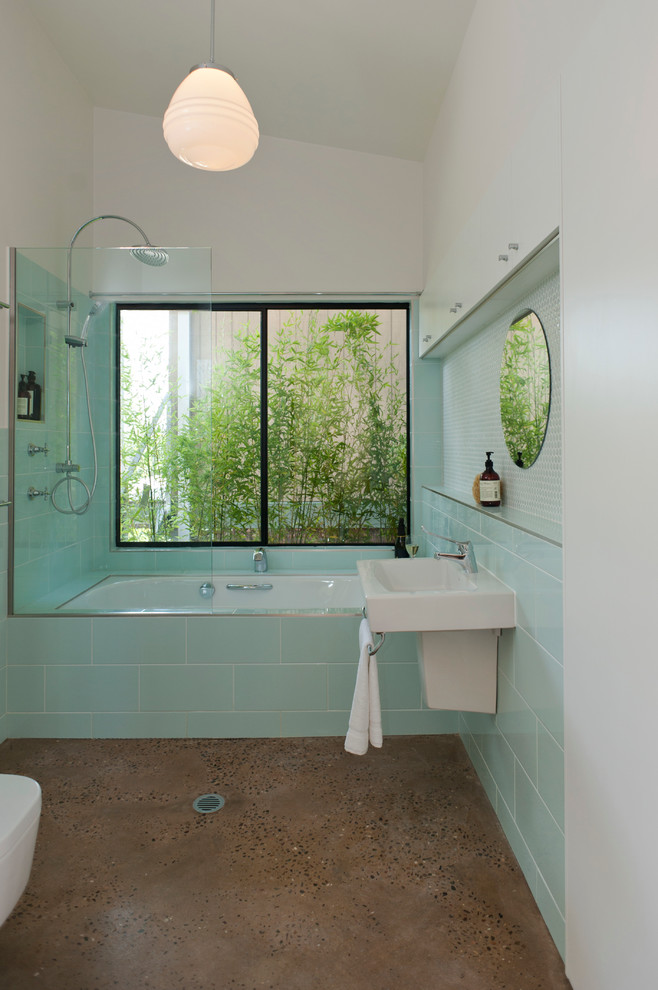 Contemporary bathroom in Sydney with a wall-mount sink, a drop-in tub, a shower/bathtub combo, green tile, white walls and concrete floors.