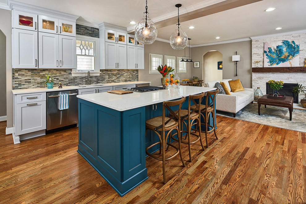 This is an example of a mid-sized transitional galley open plan kitchen in Charlotte with an undermount sink, recessed-panel cabinets, turquoise cabinets, quartz benchtops, stainless steel appliances, medium hardwood floors, with island, white benchtop, exposed beam, brown floor, multi-coloured splashback and mosaic tile splashback.
