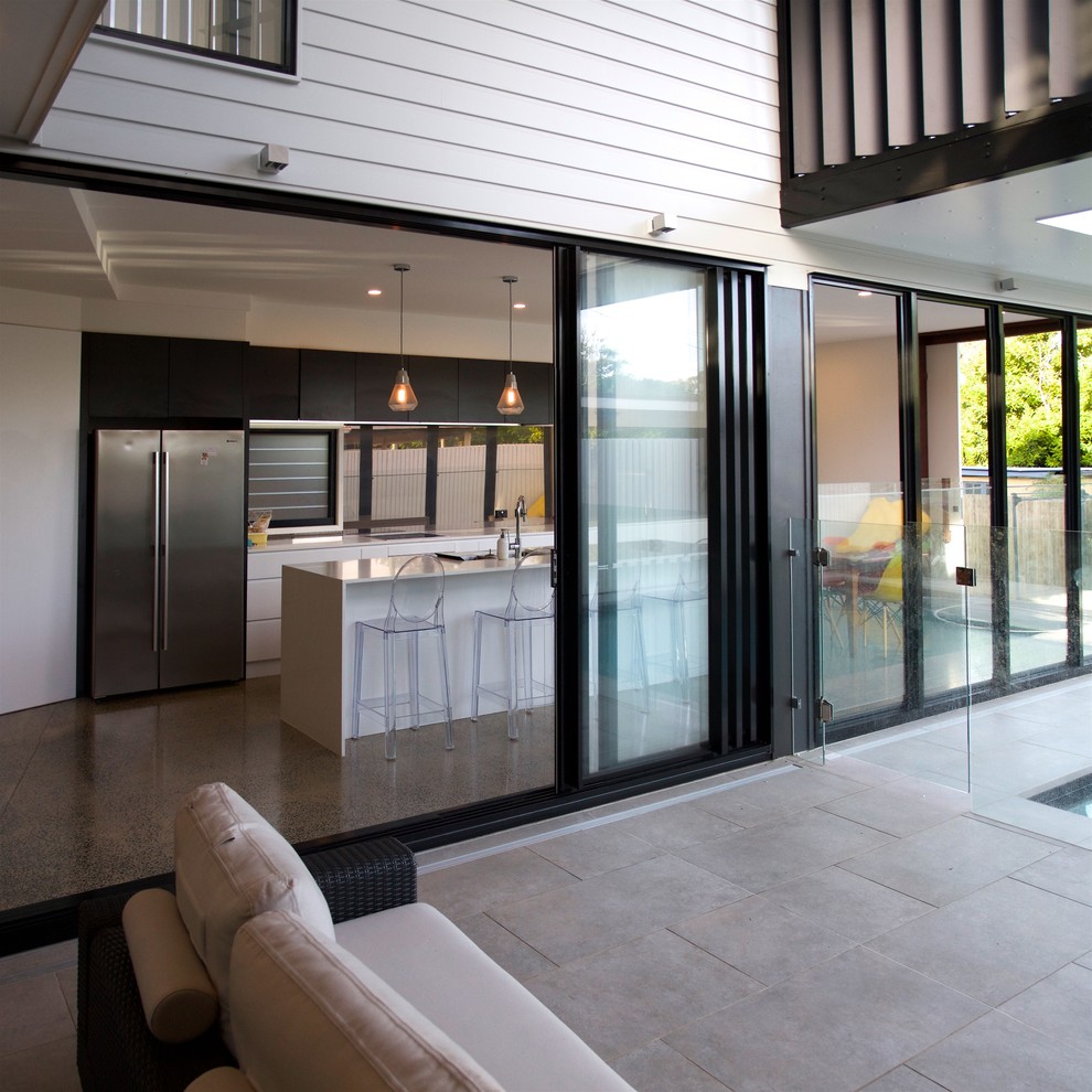 This is an example of a mid-sized contemporary galley eat-in kitchen in Brisbane with an undermount sink, recessed-panel cabinets, white cabinets, stainless steel appliances, concrete floors and with island.
