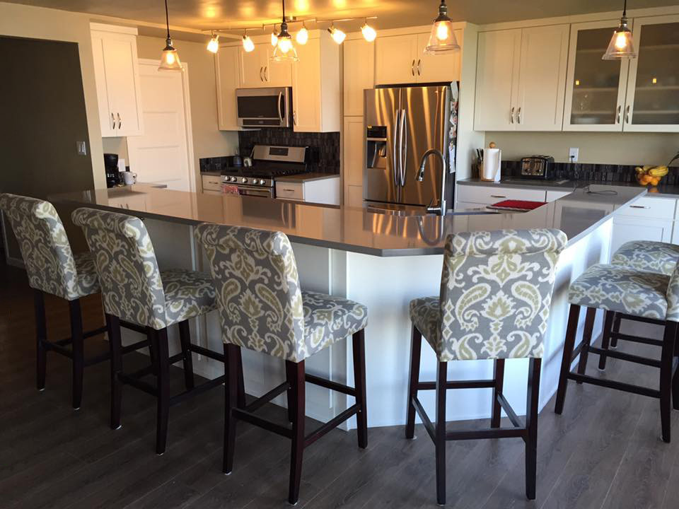 Example of a mid-sized transitional l-shaped open concept kitchen design in Seattle with an undermount sink, shaker cabinets, white cabinets, quartzite countertops, metallic backsplash, glass tile backsplash, stainless steel appliances and an island