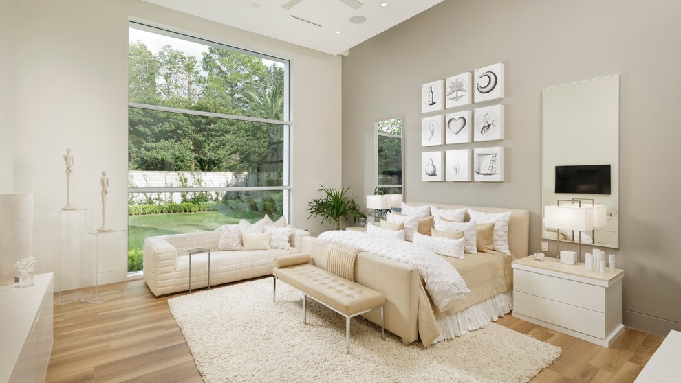 This is an example of a contemporary master bedroom in Houston with beige walls, light hardwood floors and beige floor.
