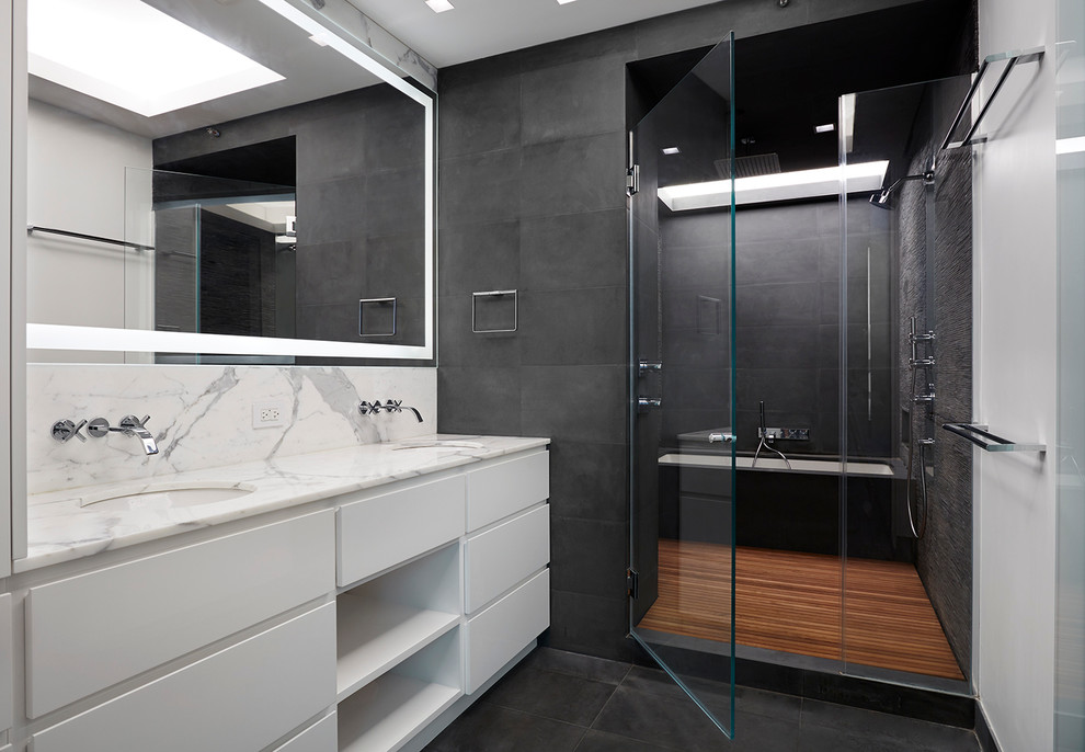 Photo of a large modern master bathroom in New York with an undermount sink, white cabinets, marble benchtops, a drop-in tub, a shower/bathtub combo, gray tile, multi-coloured walls, ceramic floors and flat-panel cabinets.
