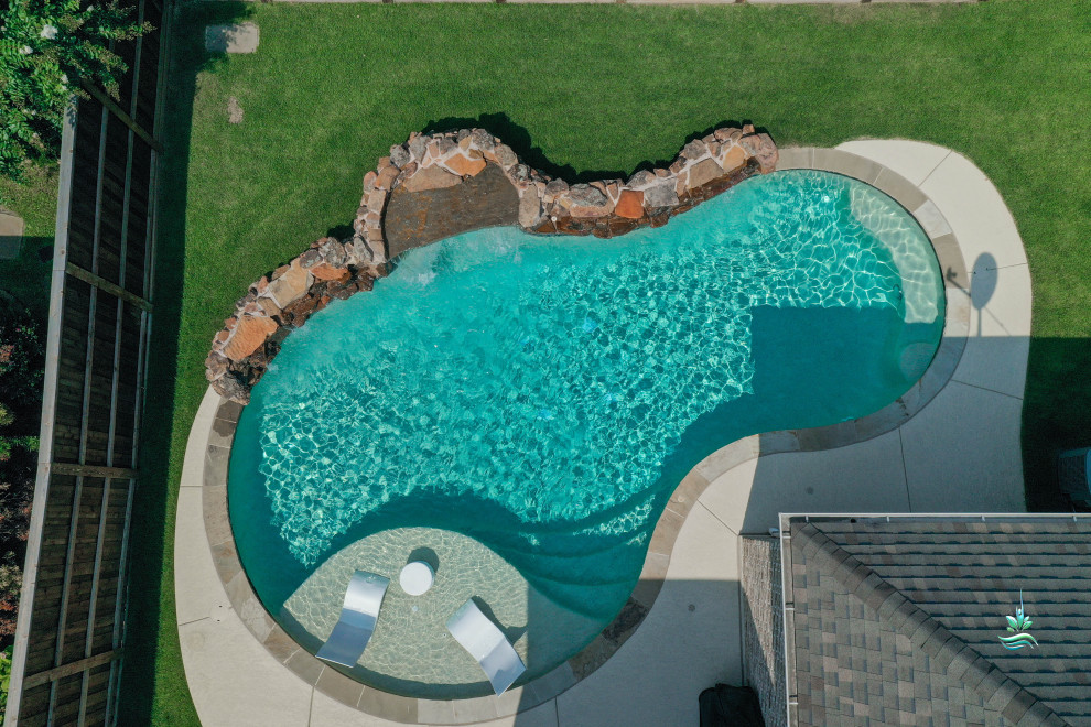 Inspiration for a mid-sized backyard custom-shaped natural pool in Dallas with with privacy feature and stamped concrete.