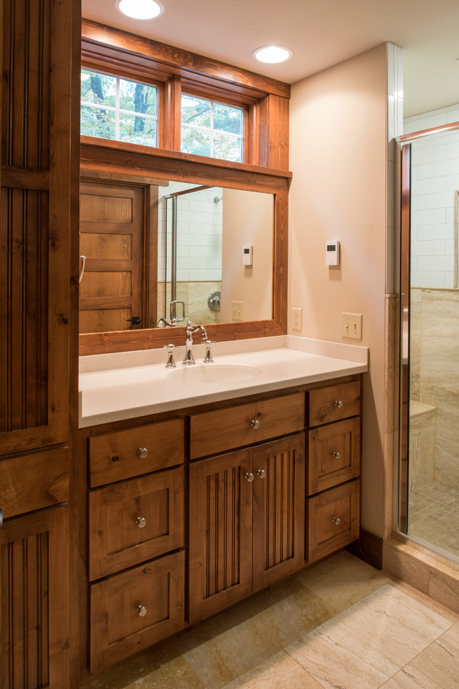 Photo of a mid-sized arts and crafts master bathroom in Minneapolis with shaker cabinets, medium wood cabinets, an alcove shower, a two-piece toilet, beige tile, stone tile, beige walls, travertine floors, an undermount sink, engineered quartz benchtops, beige floor and a hinged shower door.