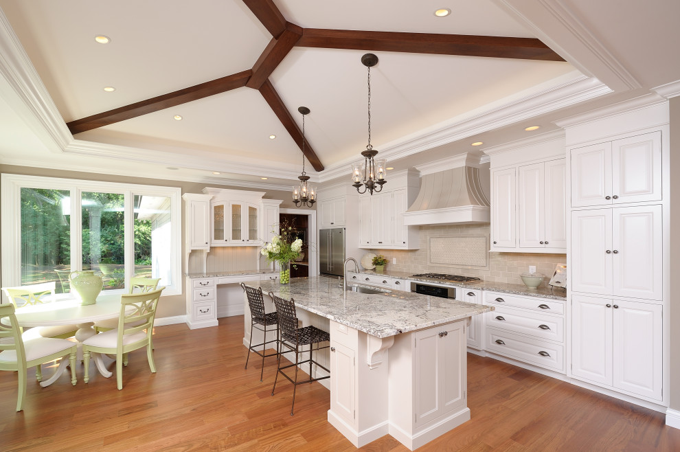 Inspiration for a mid-sized traditional l-shaped kitchen with an undermount sink, flat-panel cabinets, white cabinets, beige splashback, stainless steel appliances, medium hardwood floors, with island, brown floor, multi-coloured benchtop and recessed.