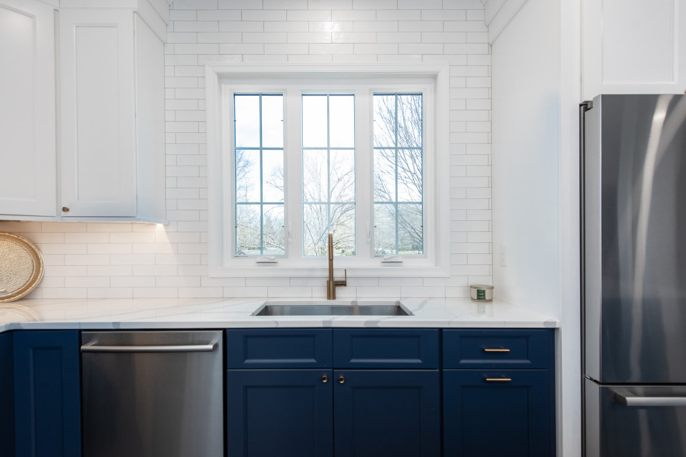 Foto på ett mellanstort vintage vit kök, med en undermonterad diskho, luckor med infälld panel, blå skåp, bänkskiva i kvarts, vitt stänkskydd, stänkskydd i tunnelbanekakel, rostfria vitvaror, klinkergolv i keramik, flera köksöar och grått golv
