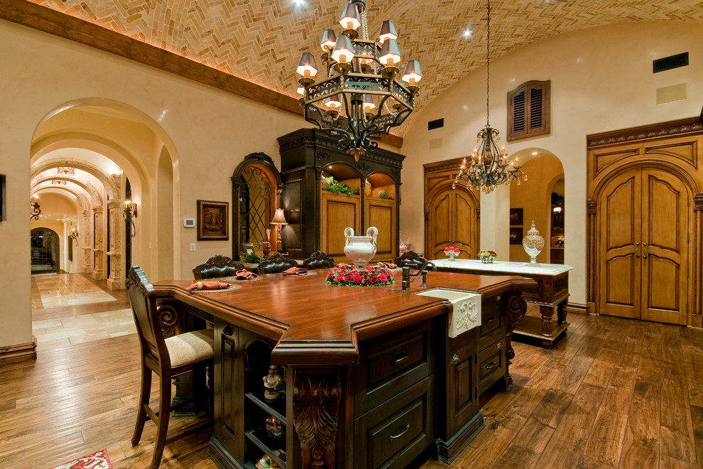 Example of a huge transitional u-shaped medium tone wood floor kitchen pantry design in Phoenix with a farmhouse sink, raised-panel cabinets, medium tone wood cabinets, wood countertops, beige backsplash, mosaic tile backsplash, paneled appliances and two islands