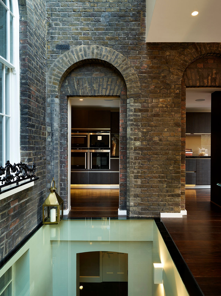 This is an example of a traditional hallway in London with brown walls and medium hardwood floors.
