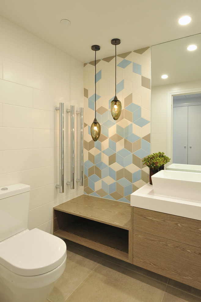 This is an example of a mid-sized contemporary bathroom in Melbourne with flat-panel cabinets, medium wood cabinets, a one-piece toilet, multi-coloured tile, porcelain tile, white walls, porcelain floors, a vessel sink and engineered quartz benchtops.