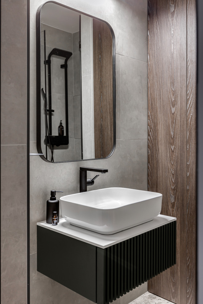 Inspiration för ett mellanstort funkis vit vitt badrum med dusch, med svarta skåp, en dusch i en alkov, en vägghängd toalettstol, grå kakel, porslinskakel, grå väggar, klinkergolv i porslin, ett nedsänkt handfat, bänkskiva i akrylsten, grått golv, dusch med gångjärnsdörr och släta luckor