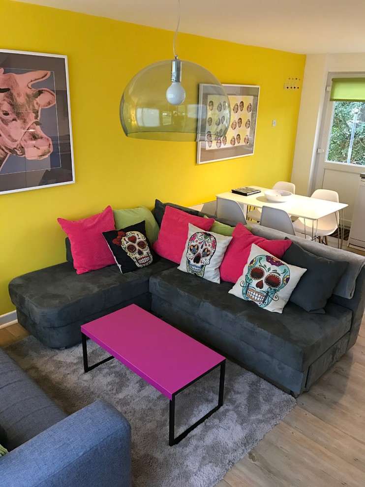 Small eclectic open concept living room in Gloucestershire with yellow walls and vinyl floors.