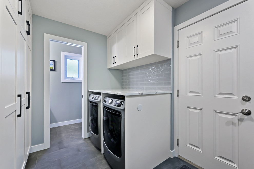Inspiration for a medium sized contemporary u-shaped utility room in Calgary with recessed-panel cabinets, white cabinets, engineered stone countertops, grey splashback, metro tiled splashback, grey walls, ceramic flooring, a side by side washer and dryer, grey floors and white worktops.