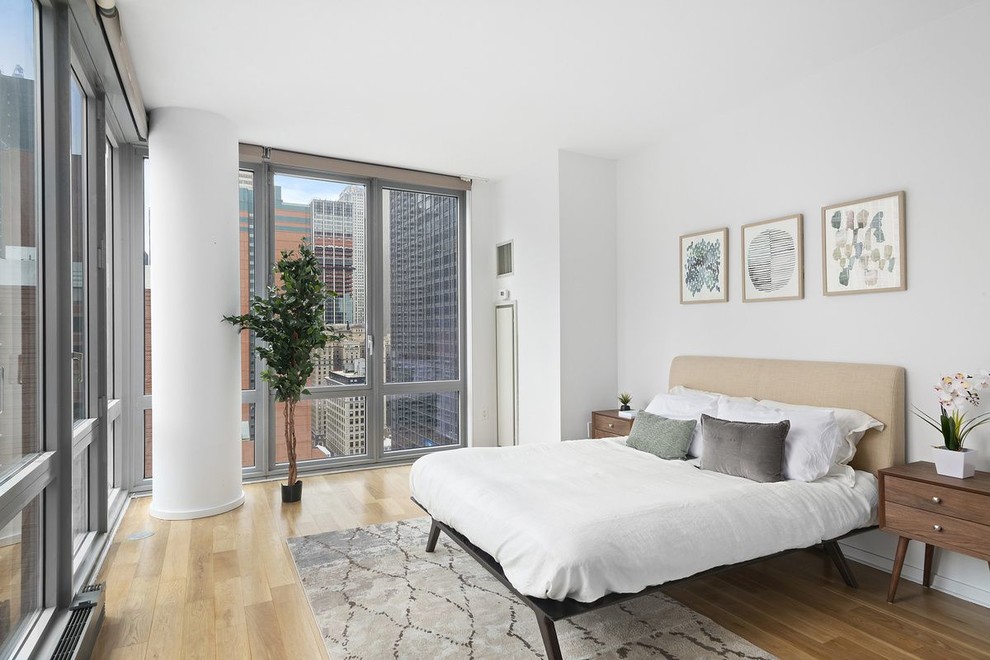 Photo of a contemporary bedroom in New York with white walls, light hardwood floors and beige floor.