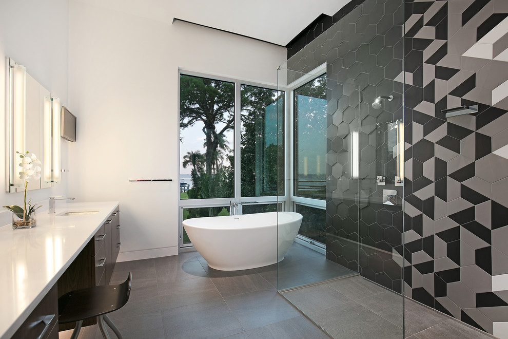 Large modern master bathroom in Tampa with flat-panel cabinets, brown cabinets, a freestanding tub, a curbless shower, a wall-mount toilet, black and white tile, ceramic tile, white walls, porcelain floors, an undermount sink, engineered quartz benchtops, grey floor, a hinged shower door and white benchtops.