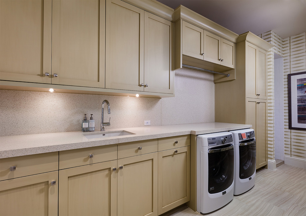 This is an example of a large traditional single-wall dedicated laundry room in Other with an undermount sink, recessed-panel cabinets, light wood cabinets, recycled glass benchtops, beige walls, ceramic floors, a side-by-side washer and dryer, beige floor and beige benchtop.