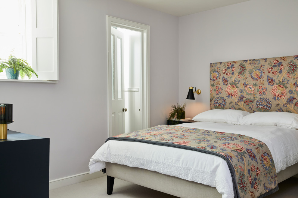 This is an example of a medium sized traditional guest bedroom in London with purple walls, carpet and grey floors.