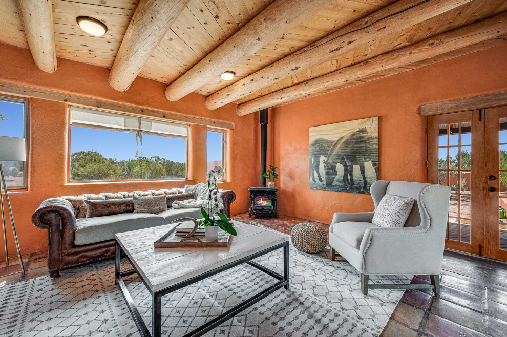 This is an example of a mid-sized enclosed living room in Other with orange walls, terra-cotta floors, a corner fireplace, a metal fireplace surround, no tv, orange floor and exposed beam.