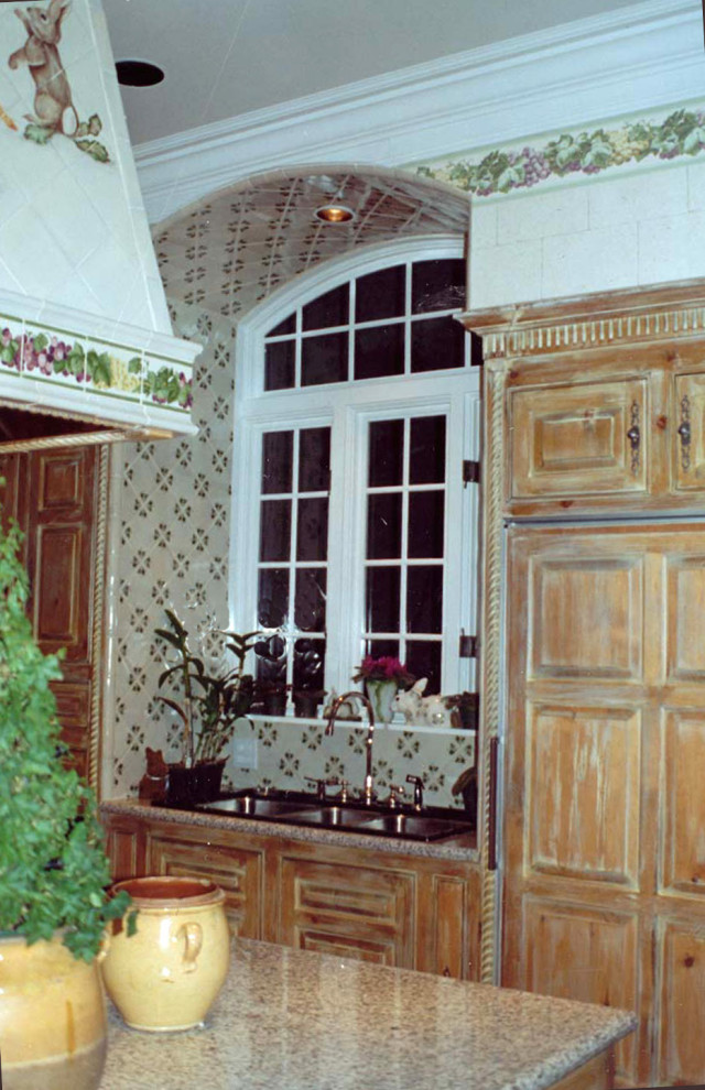 Foto di un cucina con isola centrale di medie dimensioni con lavello a tripla vasca, ante con bugna sagomata, ante con finitura invecchiata, top in granito e elettrodomestici da incasso