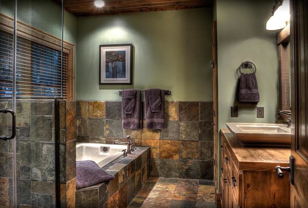 Photo of a country master bathroom in Minneapolis with distressed cabinets, a drop-in tub, a corner shower, slate, green walls, slate floors, a vessel sink, wood benchtops, a hinged shower door and multi-coloured floor.