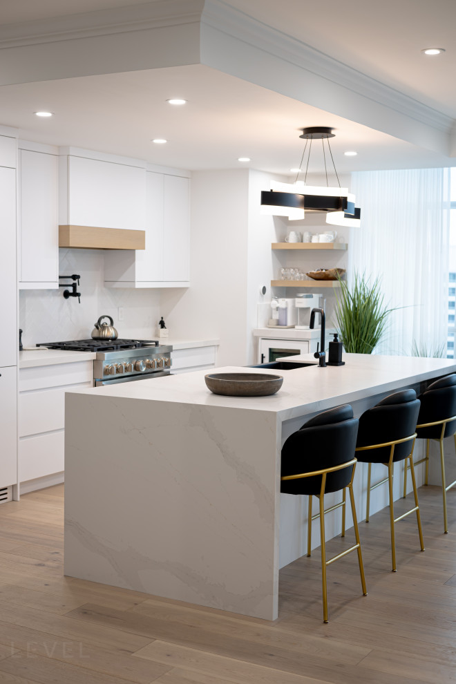 Mid-sized trendy single-wall light wood floor and brown floor open concept kitchen photo in Toronto with an undermount sink, flat-panel cabinets, white cabinets, quartz countertops, white backsplash, ceramic backsplash, paneled appliances, an island and multicolored countertops