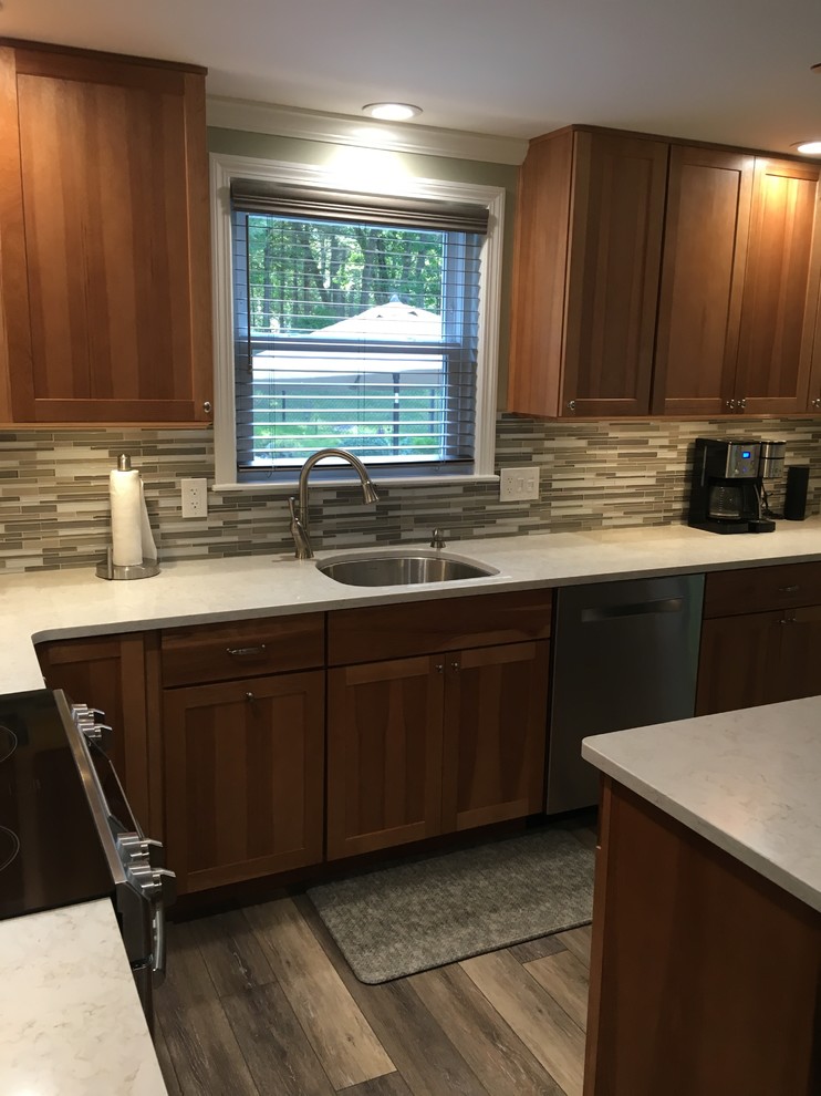 Eat-in kitchen - mid-sized transitional l-shaped laminate floor and gray floor eat-in kitchen idea in Boston with an undermount sink, shaker cabinets, light wood cabinets, quartz countertops, multicolored backsplash, glass sheet backsplash, stainless steel appliances, an island and white countertops