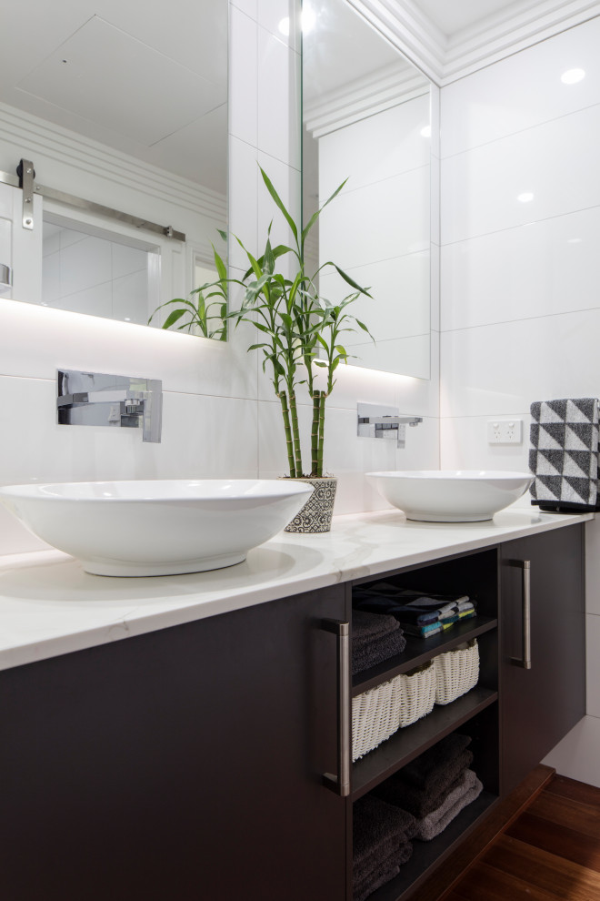 Design ideas for a contemporary bathroom in Gold Coast - Tweed with flat-panel cabinets, dark wood cabinets, white tile, dark hardwood floors, a vessel sink, brown floor, white benchtops, a double vanity and a floating vanity.