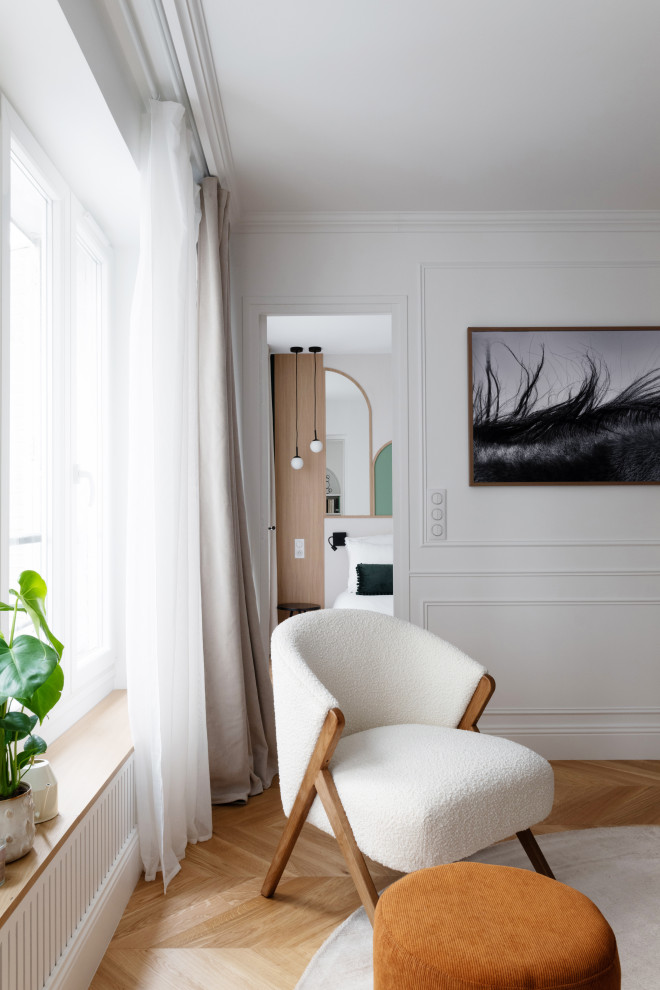 На фото: открытая гостиная комната среднего размера, в белых тонах с отделкой деревом:: освещение в стиле неоклассика (современная классика) с белыми стенами, светлым паркетным полом, телевизором на стене, коричневым полом и панелями на стенах с