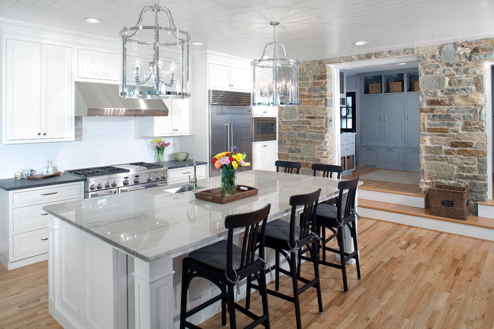 Inspiration for a traditional galley kitchen in Baltimore with with island, an undermount sink, shaker cabinets, white cabinets, white splashback, subway tile splashback, stainless steel appliances and light hardwood floors.