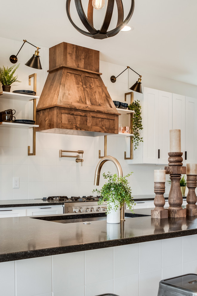 Inspiration for a mid-sized cottage galley light wood floor and beige floor eat-in kitchen remodel in Denver with an undermount sink, shaker cabinets, white cabinets, white backsplash, ceramic backsplash, stainless steel appliances, an island and black countertops