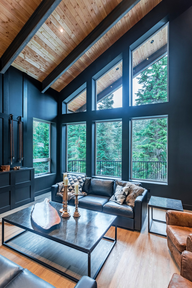 This is an example of an expansive modern open concept living room in Vancouver with vinyl floors, a wood stove, a freestanding tv, brown floor and black walls.