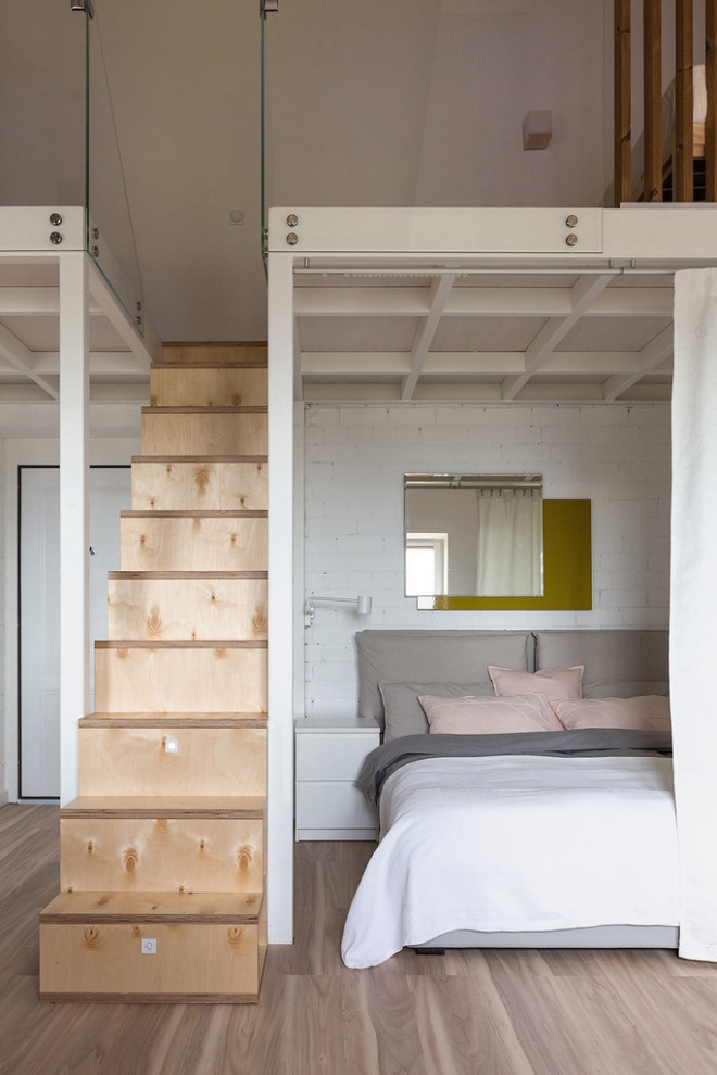 Scandinavian master bedroom with white walls, laminate floors, beige floor and brick walls.