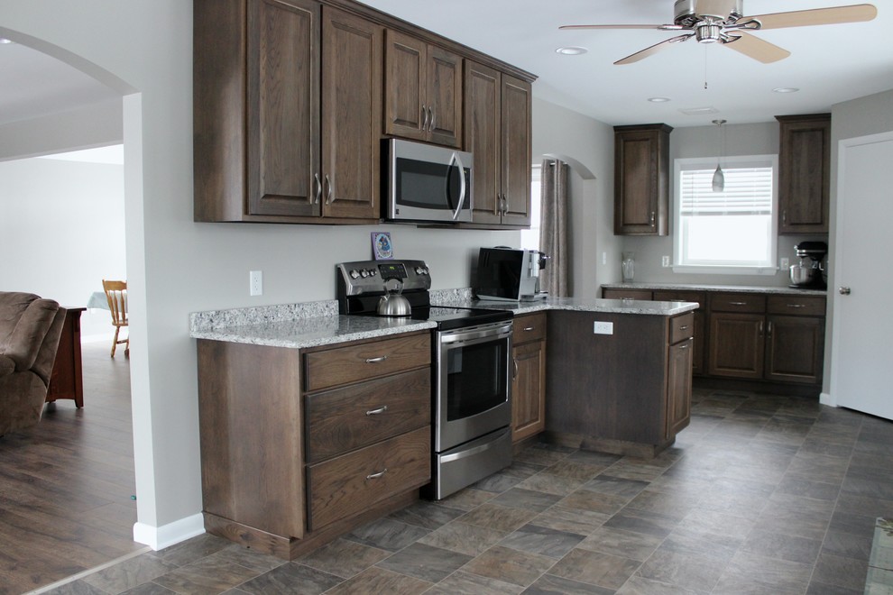 Large transitional linoleum floor enclosed kitchen photo in Philadelphia with an undermount sink, raised-panel cabinets, dark wood cabinets, quartz countertops, stainless steel appliances and a peninsula