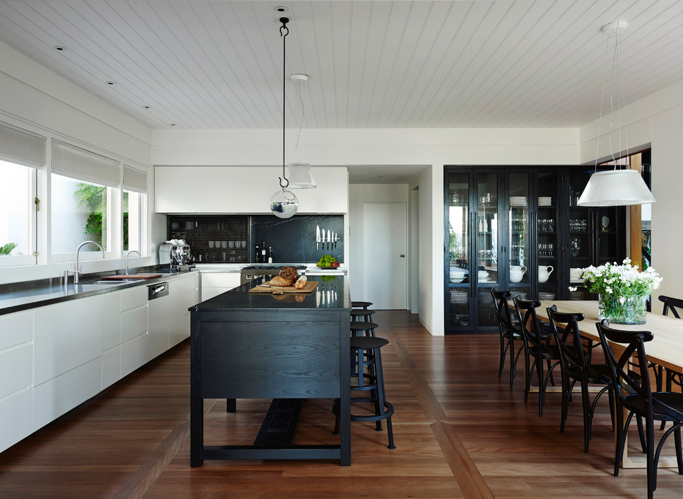 Photo of a contemporary kitchen in Sydney with flat-panel cabinets, white cabinets, black splashback, stainless steel appliances, medium hardwood floors and with island.