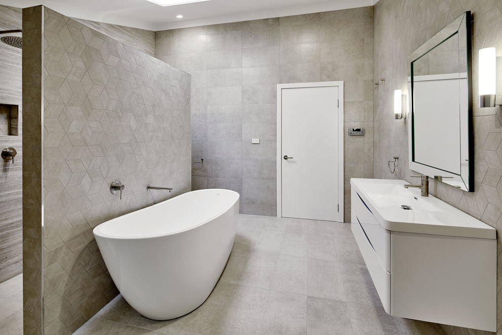 This is an example of a large contemporary master bathroom in Sydney with furniture-like cabinets, white cabinets, a freestanding tub, an open shower, a one-piece toilet, beige tile, porcelain tile, beige walls, porcelain floors, an integrated sink, engineered quartz benchtops, beige floor and an open shower.