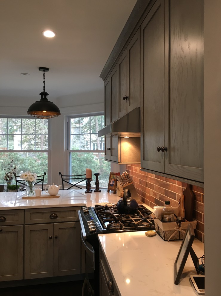 Inspiration for a large country l-shaped eat-in kitchen in Philadelphia with a farmhouse sink, shaker cabinets, grey cabinets, quartz benchtops, red splashback, brick splashback, stainless steel appliances, dark hardwood floors, with island, brown floor and white benchtop.