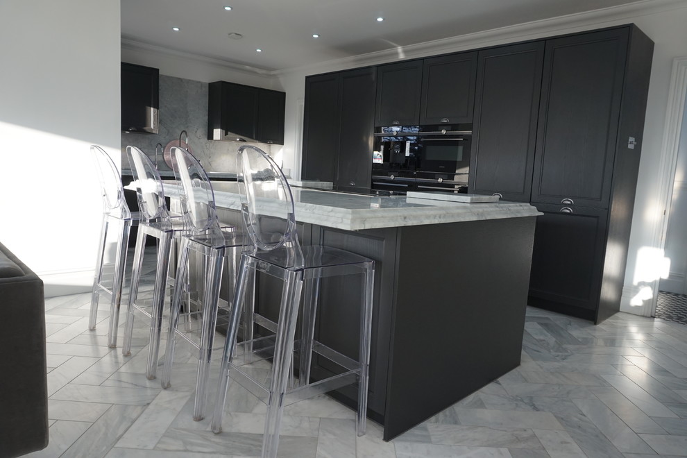 This is an example of a large traditional single-wall open plan kitchen in Essex with an undermount sink, shaker cabinets, grey cabinets, marble benchtops, white splashback, marble splashback, black appliances, marble floors, with island and white floor.