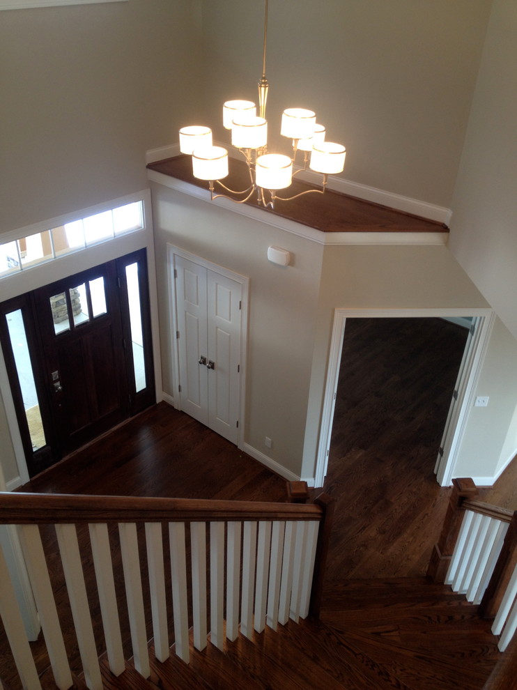 This is an example of a large arts and crafts foyer in Cincinnati with green walls, medium hardwood floors, a single front door and a dark wood front door.