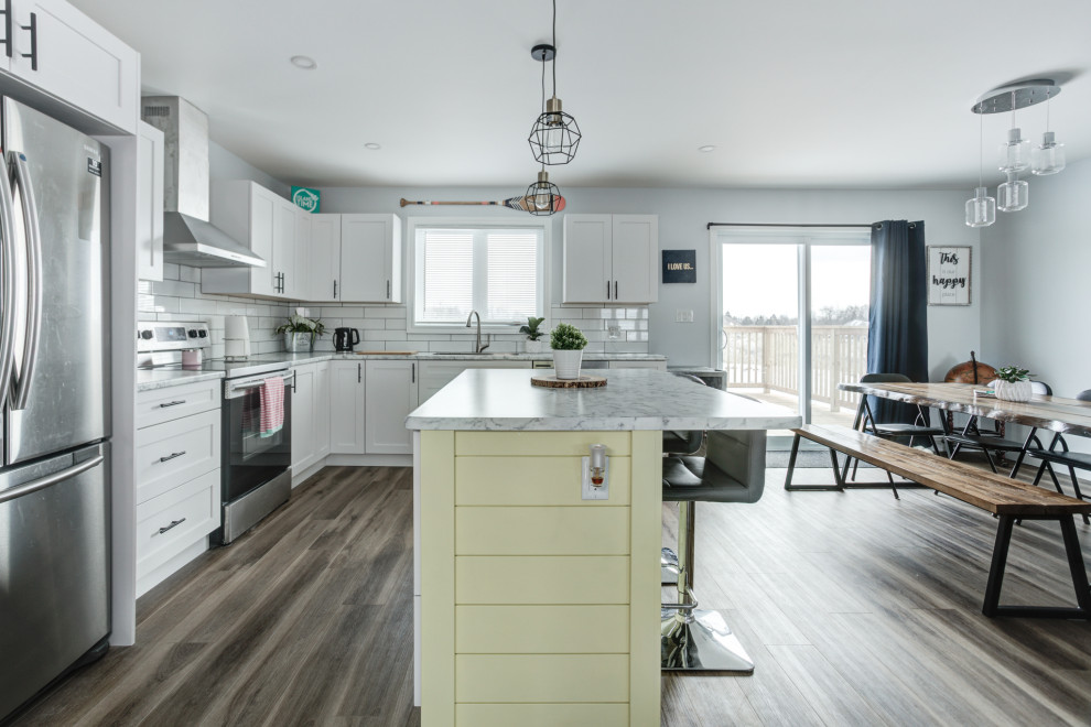 Example of a minimalist vinyl floor and brown floor eat-in kitchen design with shaker cabinets, white cabinets, ceramic backsplash and stainless steel appliances