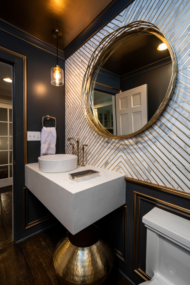 This is an example of a small traditional powder room in Indianapolis with white cabinets, a one-piece toilet, white tile, marble, blue walls, medium hardwood floors, a vessel sink, engineered quartz benchtops, brown floor, white benchtops, a floating vanity and panelled walls.