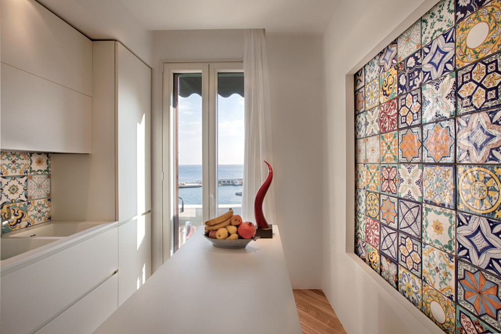 Small mediterranean single-wall separate kitchen in Other with an integrated sink, flat-panel cabinets, white cabinets, solid surface benchtops, multi-coloured splashback, ceramic splashback, stainless steel appliances, light hardwood floors, with island, yellow floor and white benchtop.