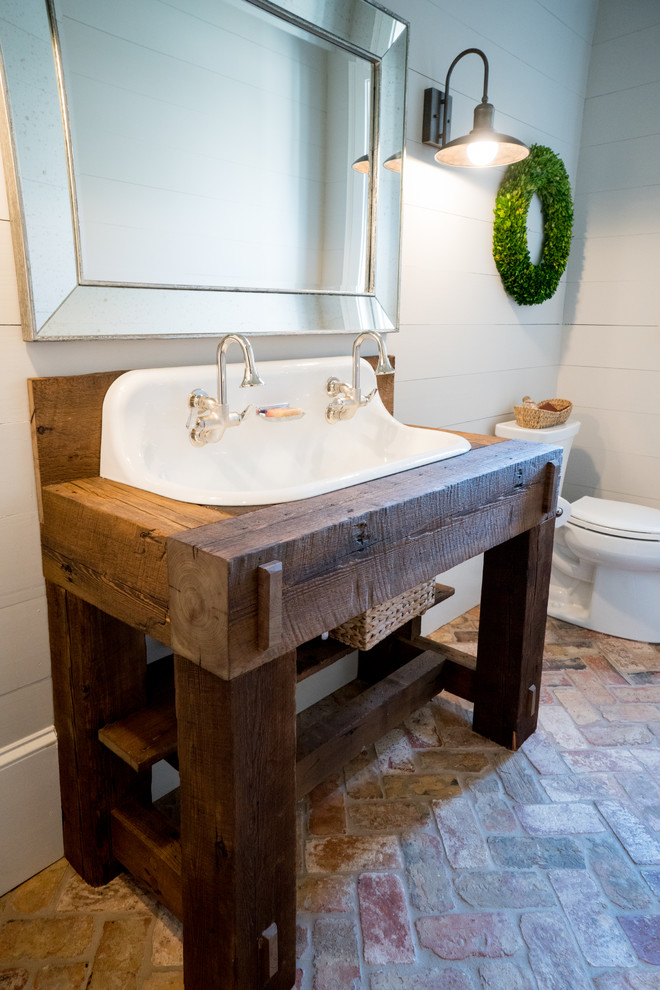 Photo of a mid-sized country bathroom in Atlanta with open cabinets, grey walls, brick floors, a trough sink and wood benchtops.