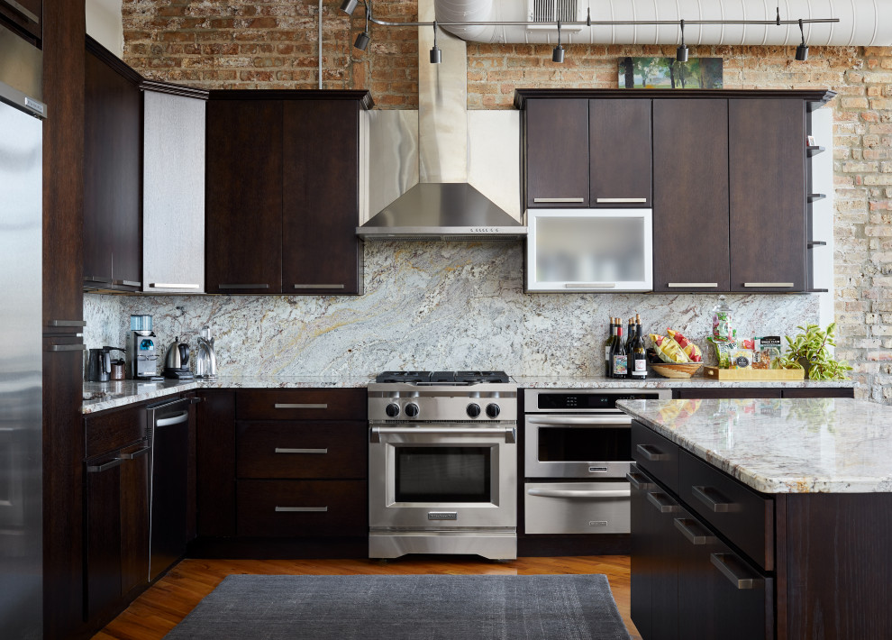 Large industrial l-shaped eat-in kitchen in Chicago with a drop-in sink, flat-panel cabinets, dark wood cabinets, marble benchtops, multi-coloured splashback, marble splashback, stainless steel appliances, medium hardwood floors and with island.