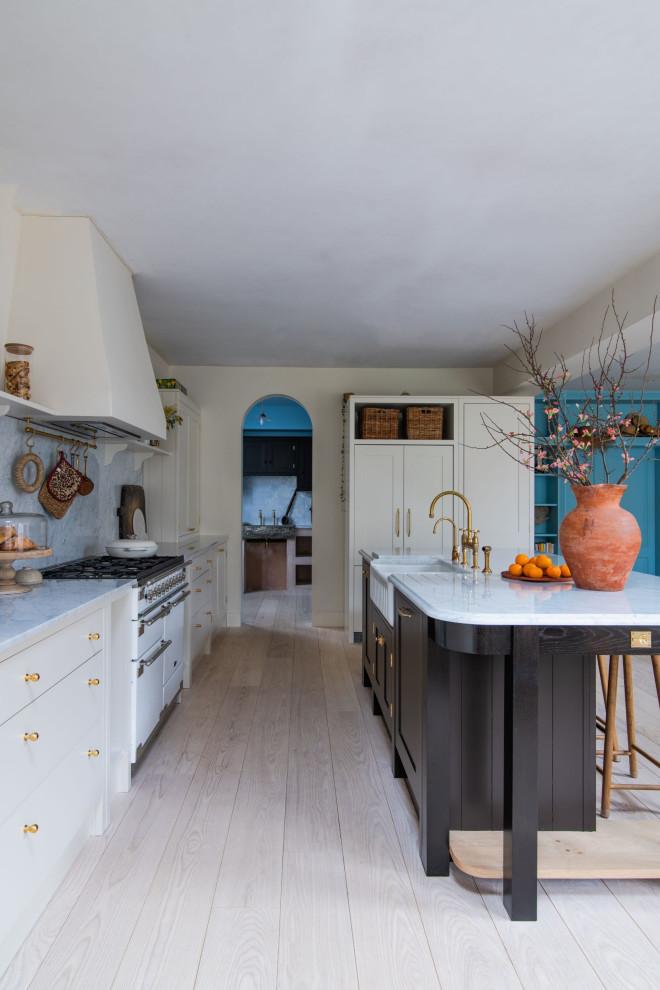 Idée de décoration pour une grande cuisine ouverte minimaliste avec un évier de ferme, un placard à porte shaker, plan de travail en marbre, une crédence en marbre, îlot, un sol beige et un plan de travail blanc.