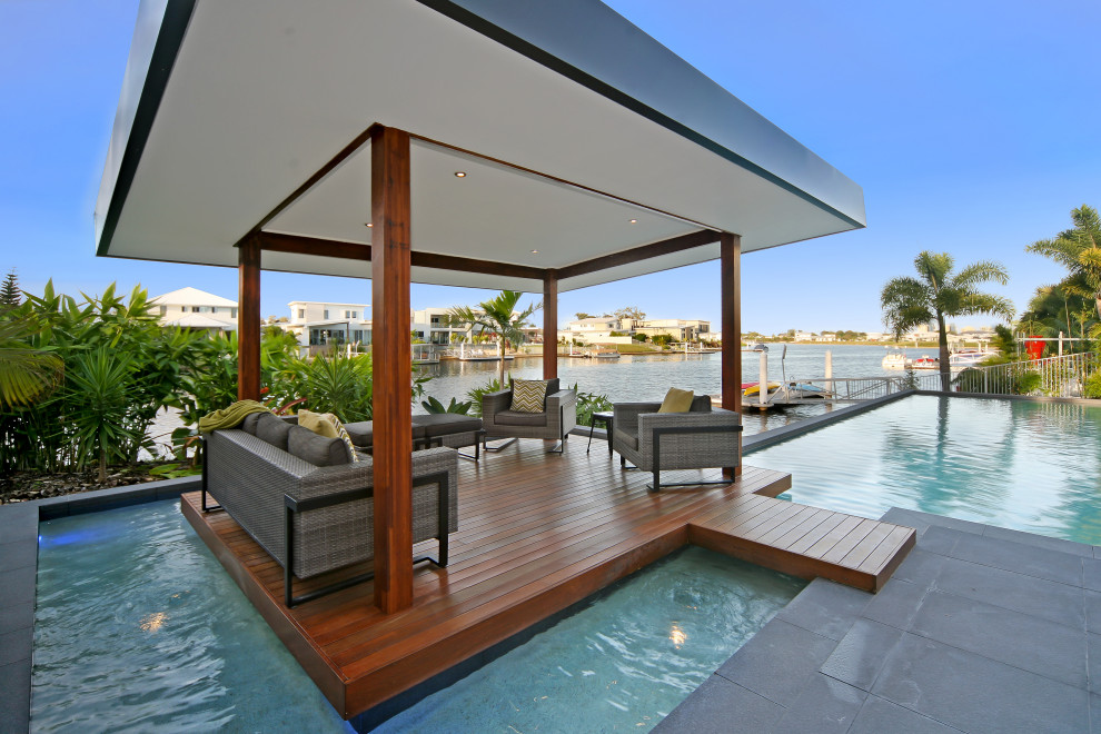 Large contemporary backyard custom-shaped pool in Brisbane with decking.
