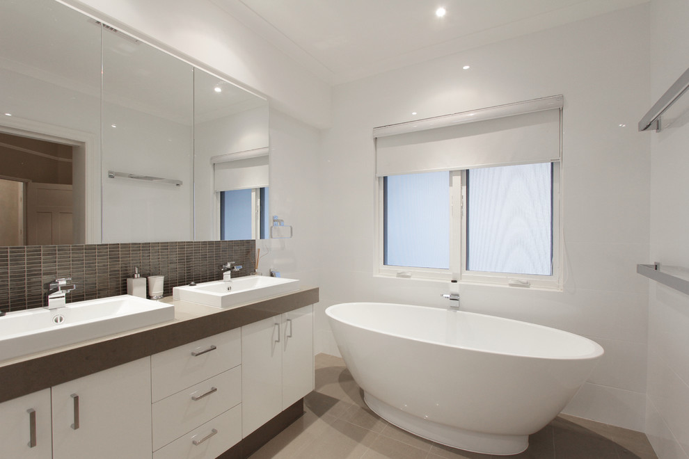 Photo of a mid-sized modern master bathroom in Perth with a drop-in sink, beaded inset cabinets, white cabinets, engineered quartz benchtops, a freestanding tub, an alcove shower, a one-piece toilet, brown tile, ceramic tile, white walls and ceramic floors.